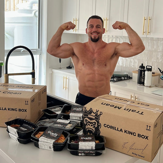 Man flexing muscles in a kitchen with 'Gorilla King' and 'Train Meal' boxes.